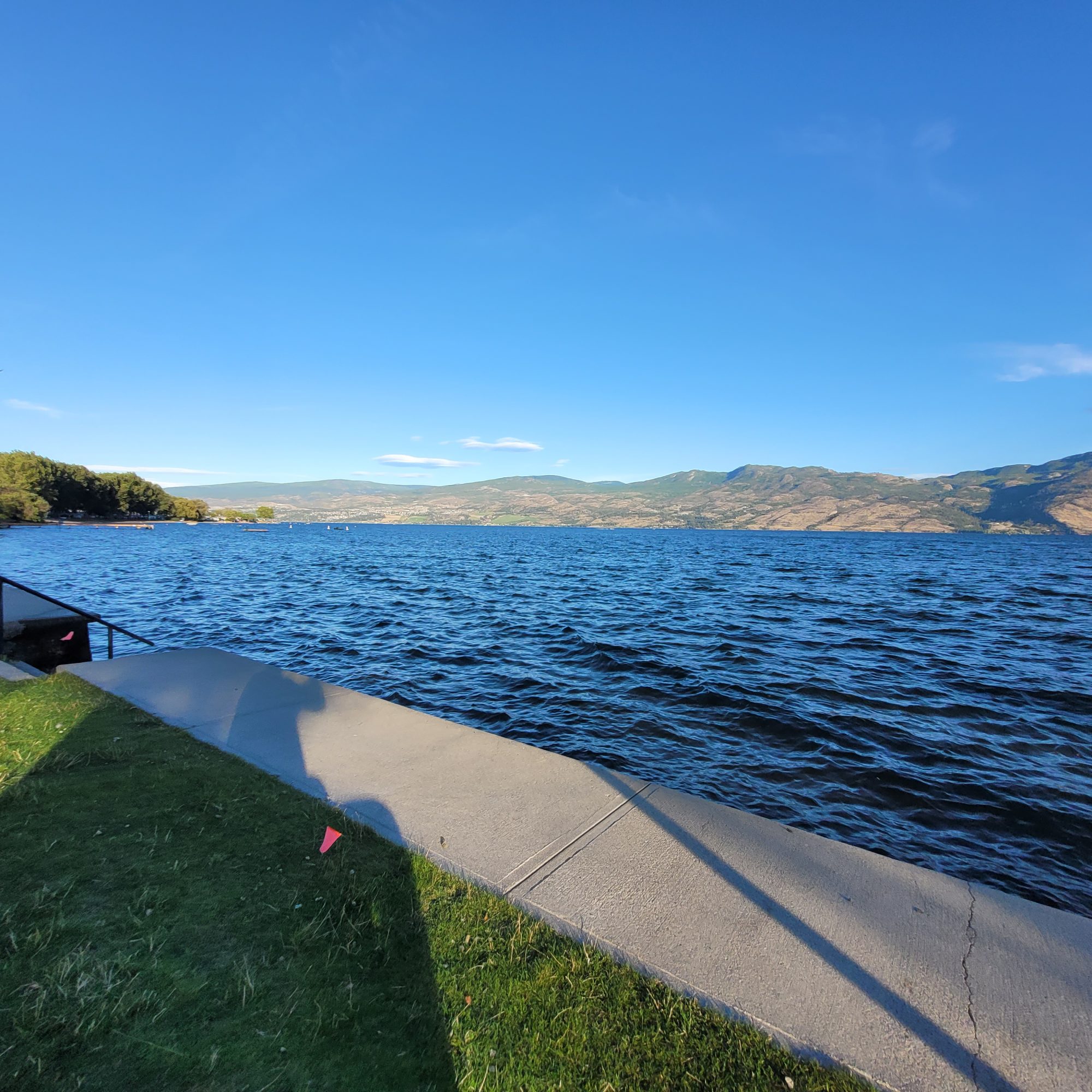 Scenic view of Okanagan Lake with clear blue skies and mountains in the background, showcasing the natural beauty of Kelowna, relevant to Kelowna Website Design's emphasis on local engagement and outdoor aesthetics.