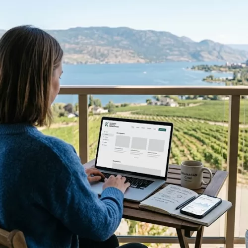 A modern entrepreneur working on a laptop prototype on a patio overlooking Lake Okanagan, illustrating affordable web design in Kelowna for local startups